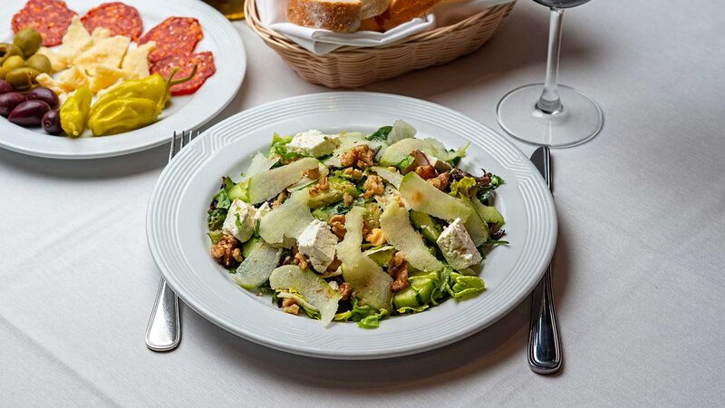 Mixed greens salad topped with walnuts, cucumber, cranberries apples and feta cheese