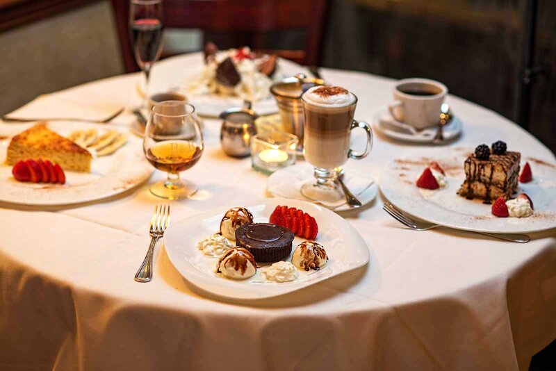 Multiple desserts on a set table with focus on chocolate cake